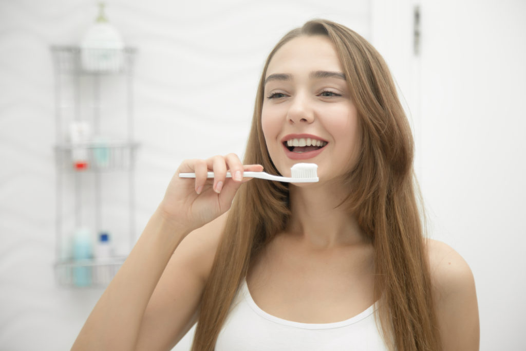 teen girl brushing teeth with braces